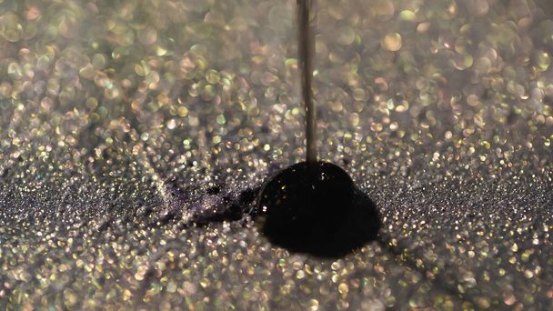 close-up zicht van zwarte vloeistof gieten op glanzende oogschaduw  - Foto, afbeelding