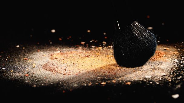 Γκρο πλαν άποψη των καλλυντικών βούρτσα σε σκόνη προσώπου σε μαύρο φόντο με φωτισμό  - Φωτογραφία, εικόνα