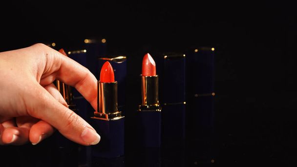 Cropped view of woman taking red lipstick on black background  - Φωτογραφία, εικόνα