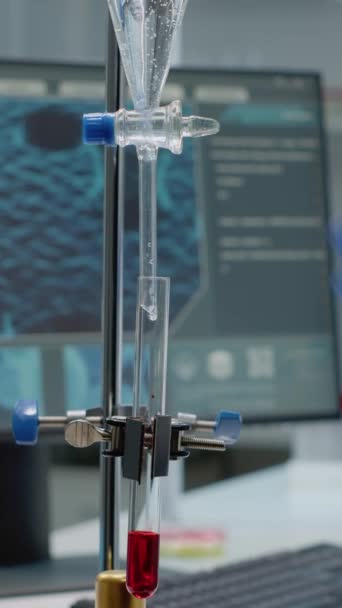 Vídeo vertical: Especialista en ciencias que utiliza un tubo de ensayo químico en el laboratorio en el escritorio con equipo de investigación. Médico operando soluciones de fluidos de mezcla de tuberías de goteo en cristalería para farmacéutica - Imágenes, Vídeo