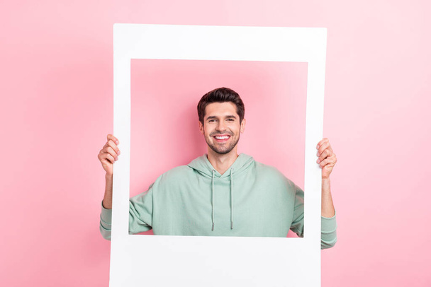 Foto de manos de persona alegre sostiene tarjeta de álbum de papel sonrisa dental aislado en el fondo de color rosa. - Foto, Imagen