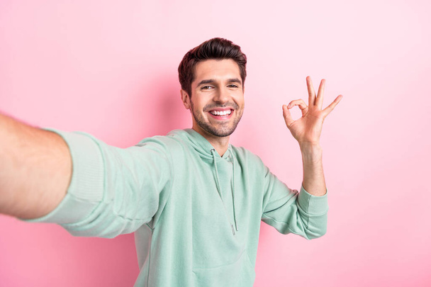 Selfie closeup cadre of attractive guy showing okey sign toothy beaming smile good job blogger lifestyle channel youtube isolated on pink color background. - Фото, зображення