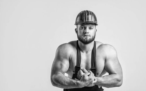 athletic guy with strong muscles in mechanic uniform, architecture, copy space. - Φωτογραφία, εικόνα