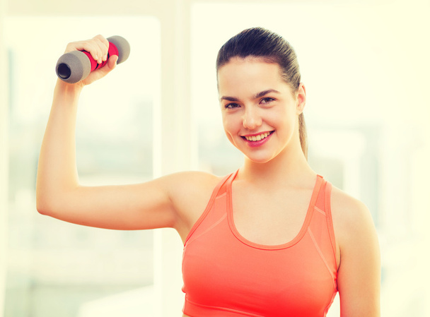 smiling teenage girl exercising with dumbbell - 写真・画像