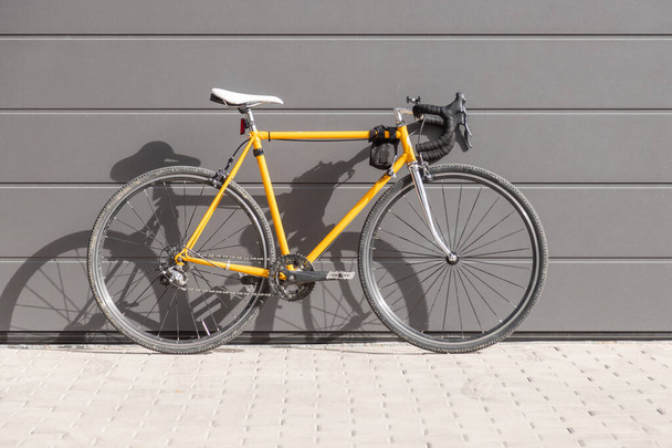 vintage yellow fixie road bike stacked on a gray wall - Foto, immagini