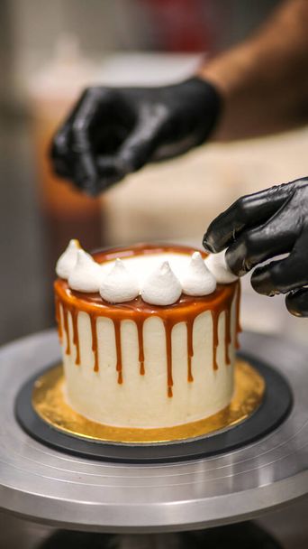 chef-kok versieren van de top van een glazuur boterroom taart - Foto, afbeelding