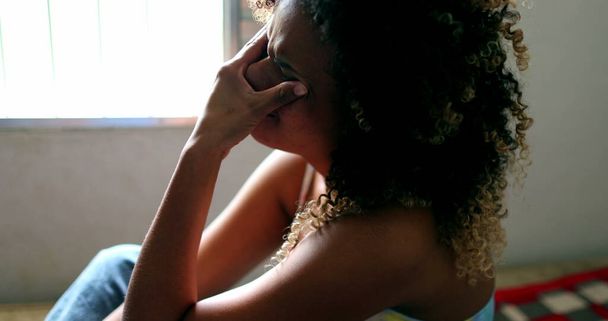 Слезливая бразильская женщина плачет, черная латиноамериканка в слезах сидит в постели - Фото, изображение