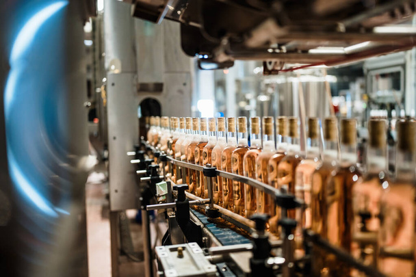 工業用ワイン瓶詰め工場のテーマ。アルコール飲料の瓶詰めと包装のための近代的な産業生産ライン.  - 写真・画像