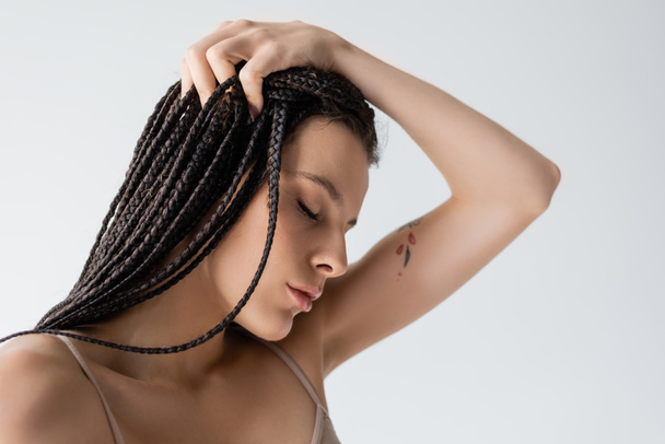 Egy fiatal tetovált nő portréja fonott hajjal, szürke hajjal.  - Fotó, kép