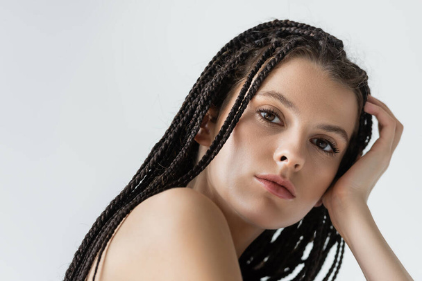 Portrait of young woman with braids looking at camera isolated on grey  - Фото, изображение