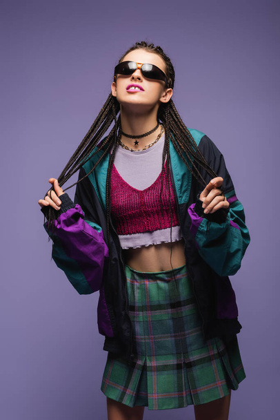 Young woman in vintage clothes and sunglasses standing isolated on purple  - Foto, Imagem