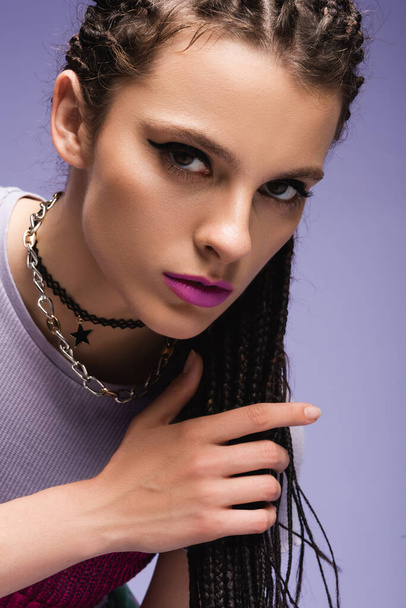 portrait of stylish woman in necklaces and makeup looking at camera isolated on purple - Photo, Image