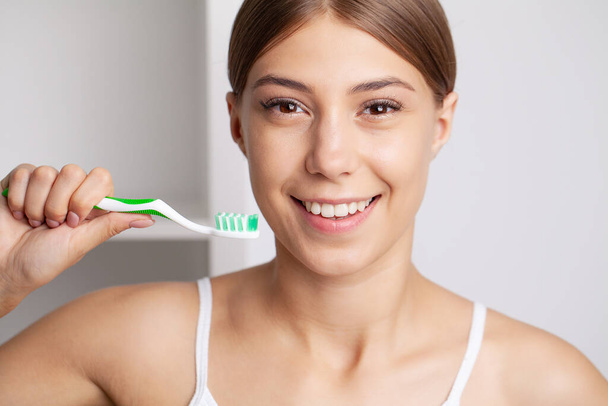 Красива молода жінка чистить зуби у ванній
. - Фото, зображення