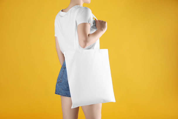 Woman with white textile bag on orange background, closeup. Space for design - Zdjęcie, obraz