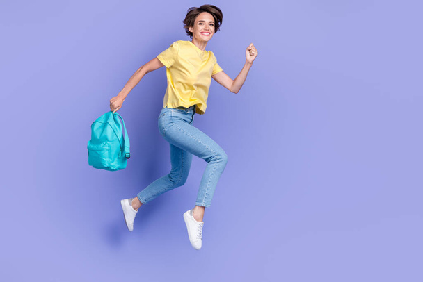 Full body portrait of excited energetic lady hold bag jumping running isolated on purple color background. - 写真・画像