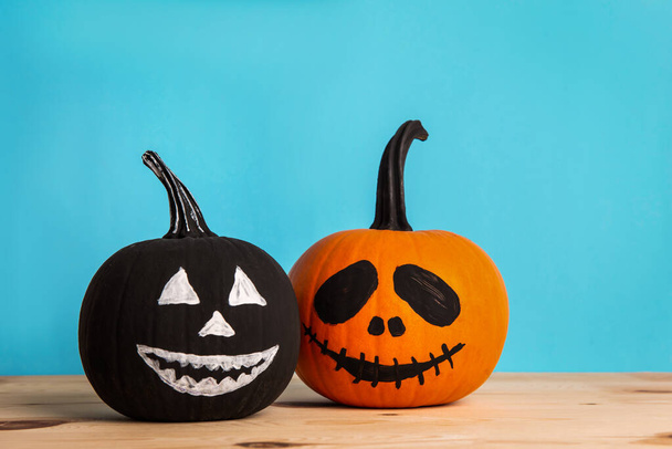 Halloween celebration. Pumpkins with spooky drawn faces on wooden table - Fotografie, Obrázek