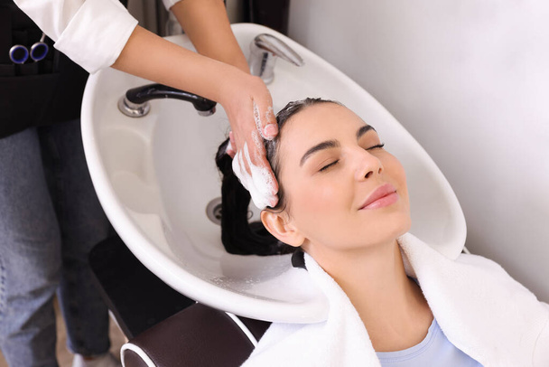 Professional hairdresser washing woman's hair in beauty salon, closeup - Foto, Imagem