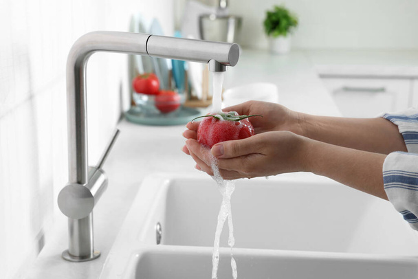 Woman washing fresh ripe tomato under tap water in kitchen, closeup - Zdjęcie, obraz
