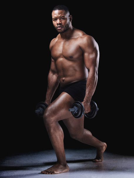 Always room fro improvement. Studio portrait of a fit young man exercising against a black background - Fotoğraf, Görsel