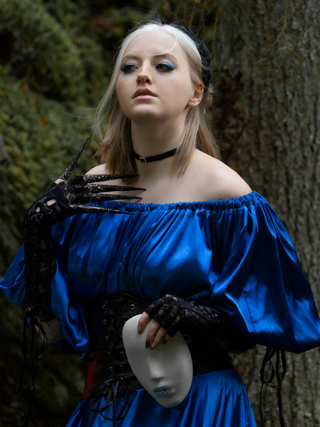 Schöne Frau in einem langen blauen Kleid, schwarzem Lederkorsett und schwarzen Spitzenhandschuhen im Wald. Waldnymphe. Mittleres Porträt. - Foto, Bild