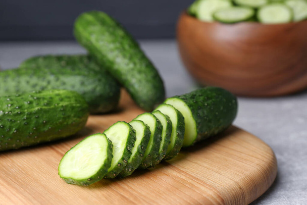 Whole and cut fresh ripe cucumbers on wooden board, closeup - Φωτογραφία, εικόνα
