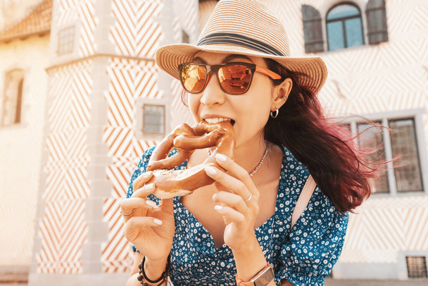 Щаслива дівчина - турист, що їсть традиційну крендель на задньому плані будинку Леденхоффа в Оснабрюку (Німеччина). - Фото, зображення