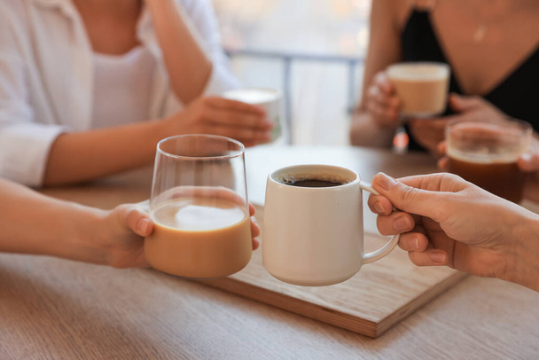 Amigos tomando café en la mesa de madera en la cafetería, primer plano - Foto, Imagen
