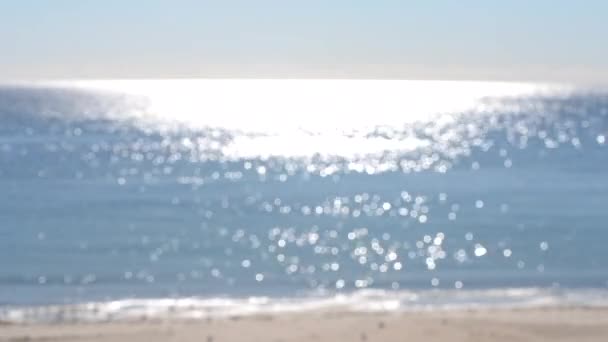 Abstraktní rozmazané pozadí.skvrny bílých odrazů zářícího slunce na modrém povrchu mořských vln, modré oblohy a písečné pláže. Moře za slunečného dne. Přírodní rozmazané bokeh textury pozadí. Bezešvé smyčky. - Záběry, video