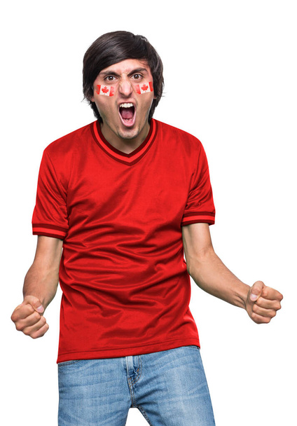 Soccer fan man with jersey and face painted with the flag of the Canada team screaming with emotion on white background. - Φωτογραφία, εικόνα