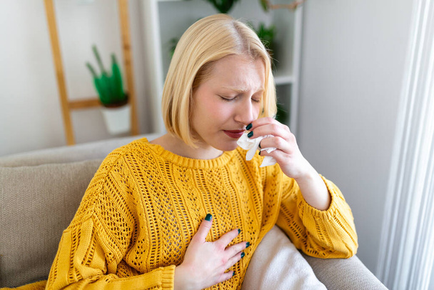 Sick Woman.Flu.Woman Caught Cold. Sneezing into Tissue. Headache. Virus .Medicines. Young Woman Infected With covid 19 Blowing Her Nose In Handkerchief. Sick woman with a headache sitting on a sofa - Foto, Imagem