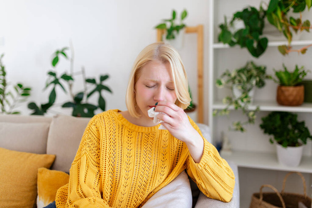 Sick Woman.Flu.Woman Caught Cold. Sneezing into Tissue. Headache. Virus .Medicines. Young Woman Infected With covid 19 Blowing Her Nose In Handkerchief. Sick woman with a headache sitting on a sofa - Foto, afbeelding
