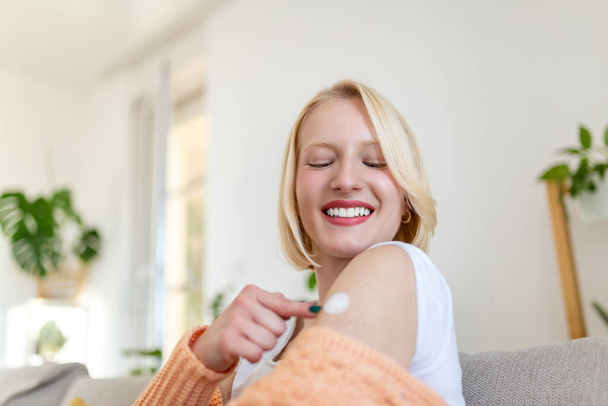 Kobieta wskazująca na jego ramię bandażem po otrzymaniu szczepionki przeciw wirusowi covid-19. Młoda kobieta pokazuje ramię po podaniu szczepionki przeciw koronawirusowi - Zdjęcie, obraz