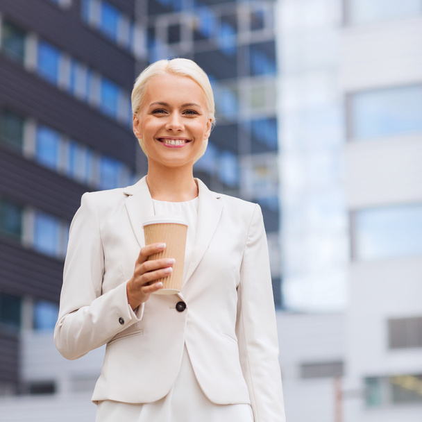 smiling businesswoman with paper cup outdoors - Foto, imagen