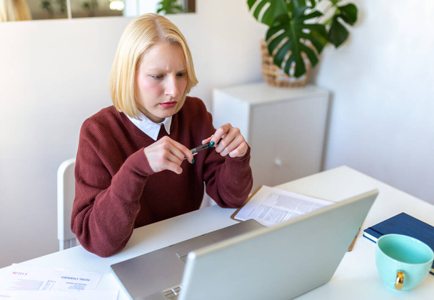 若い女性労働者が自宅のオフィスで電子メールや契約書を読んで座っている悪いニュースと混同します。 - 写真・画像