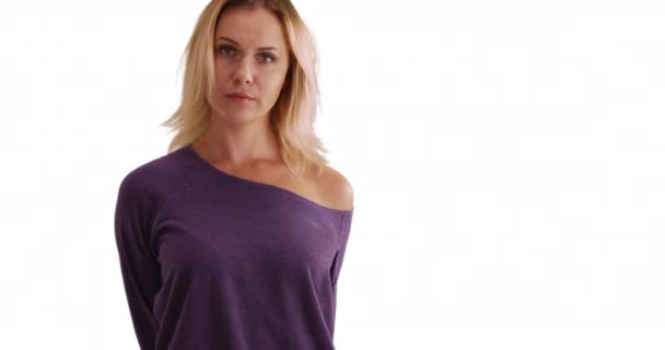Good-looking young lady posing for camera casually on solid white background. Caucasian woman in purple baggy shirt looking gently at camera on white copy space. 4k - Footage, Video