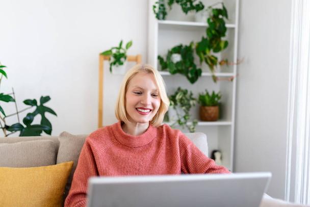 Усміхнена молода жінка використовує ноутбук вдома, дивлячись на екран, спілкуючись, одягаючи бездротовий гарнітур, що має відеоконференцію. бізнес-тренер навчання по веб-камері, онлайн-тренінги, концепція електронного коучингу
 - Фото, зображення