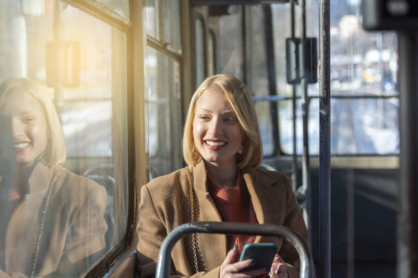 άτομα σε μέσα μαζικής μεταφοράς, επιβάτες, γυναίκα επιβάτης κοιτάζοντας την οθόνη του smartphone της - Φωτογραφία, εικόνα