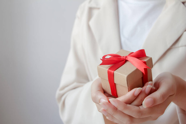 Woman hand holding gift box with red ribbon. - Foto, imagen