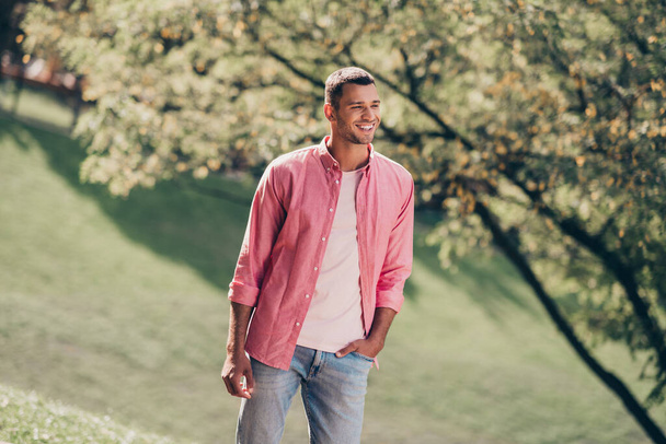Photo of attractive cute young guy dressed pink casual shirt smiling walking sunny park outdoors backyard. - Fotografie, Obrázek