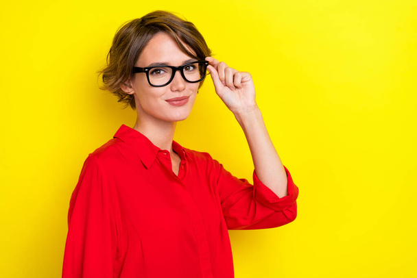 Photo of satisfied optimistic lovely woman with bob hairstyle wear red shirt hand touch glasses isolated on yellow color background. - 写真・画像