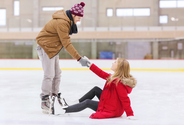 man helping women to rise up on skating rink - Fotografie, Obrázek