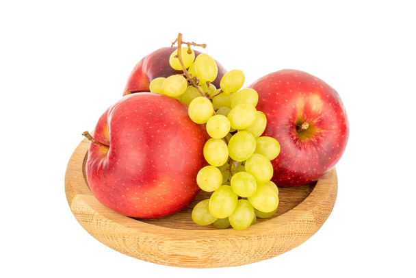 Natura morta di tre rossi e rametti di mele d'uva su un piatto di legno, macro, isolato su sfondo bianco. - Foto, immagini