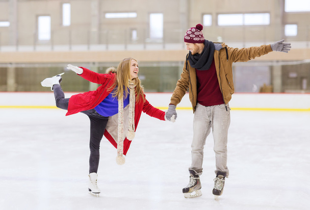 happy couple holding hands on skating rink - 写真・画像