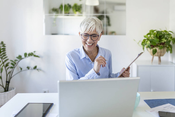 Mature businesswoman presenting charts and graphs on video call online. Middle-aged Business woman having conference call with client on laptop. Closeup business woman working laptop computer indoor. - Φωτογραφία, εικόνα