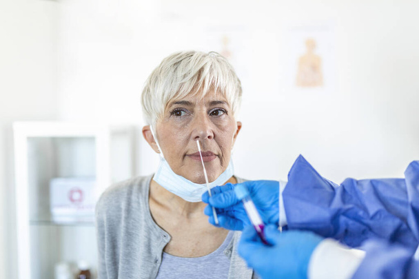 Ärztliche Laborantin im Schutzanzug nimmt Abstrich von der Nase eines kranken Patienten im Krankenhaus. Labortests für Coronavirus-Konzept. - Foto, Bild