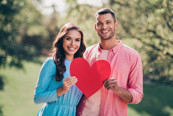 Photo of sweet pretty two people together wear casual outfits holding big red heart outside garden. - Foto, Imagem