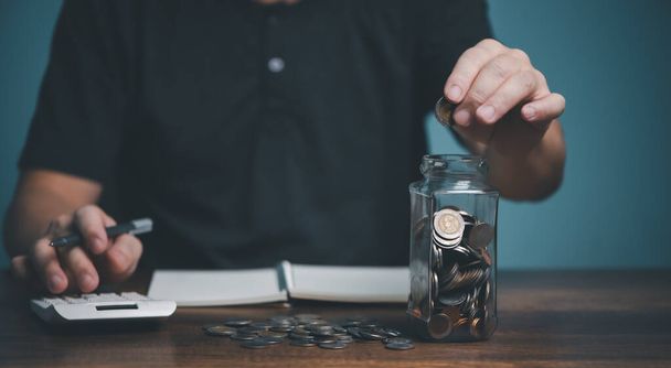 Man take a coin money into jar bottle for education, donation, saving, charity, family finance plan concept, fundraising, superannuation, financial crisis concept. - Fotó, kép