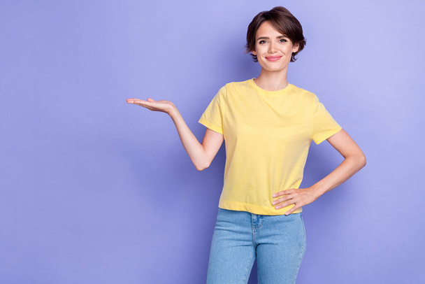 Photo of young adorable pretty nice woman touch waist wear yellow t-shirt hold abstract object for sale assistant isolated on violet color background. - Foto, afbeelding