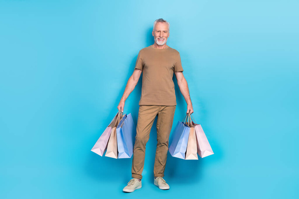 Full size portrait of cheerful aged person hands hold packages isolated on blue color background. - Fotoğraf, Görsel