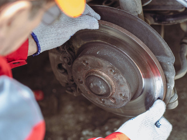 Car mechanic wearing uniform examining brake pads with caliper. Car safety system. - Fotoğraf, Görsel